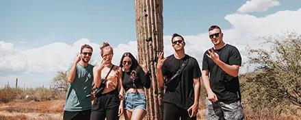 Topdeck travellers posing with a Cactus in Arizona.
