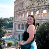 A smiling woman standing in front of the Colosseum 