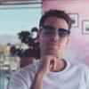 Man looking pensive at the camera, wearing sunglasses