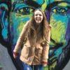 Smiling woman standing in front of graffiti art
