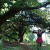 Woman standing in nature with her arms in the air with trees behind and around her