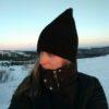 A close-up image of a woman in the snow wearing a black coat and a black, pointy hat