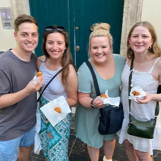 Four Topdeck travelers enjoying a snack during their trip through Rome.