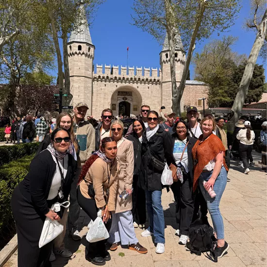 Group of people standing together and smiling outside the Gate of Salutation at Topkapı Palace in Istanbul.
