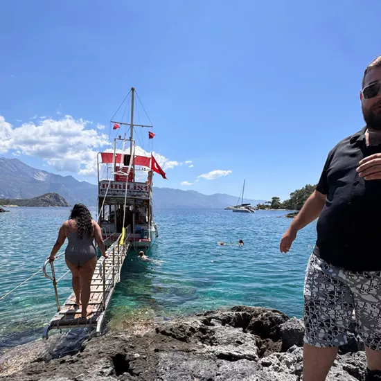 Person walking on wooden bridge to the back of a sailing boat in Turkey.