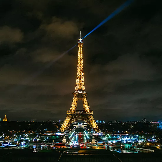 A view of the iconic Eiffel Tower of Paris, lit up at night.