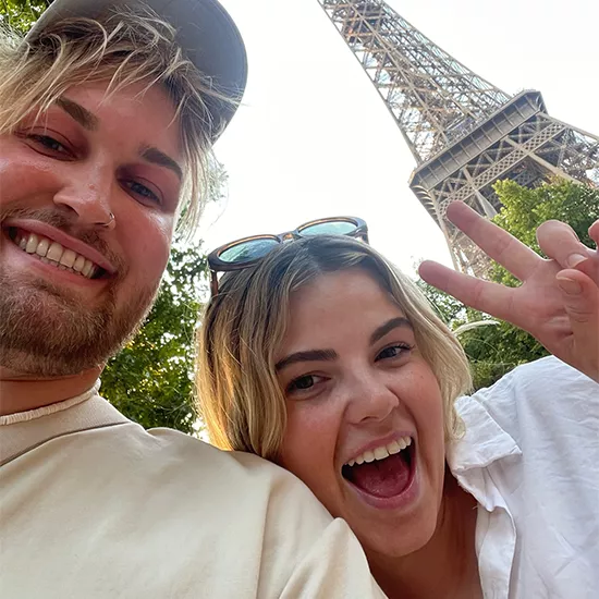 Two people posing for a selfie in front of the Eiffel Tower.