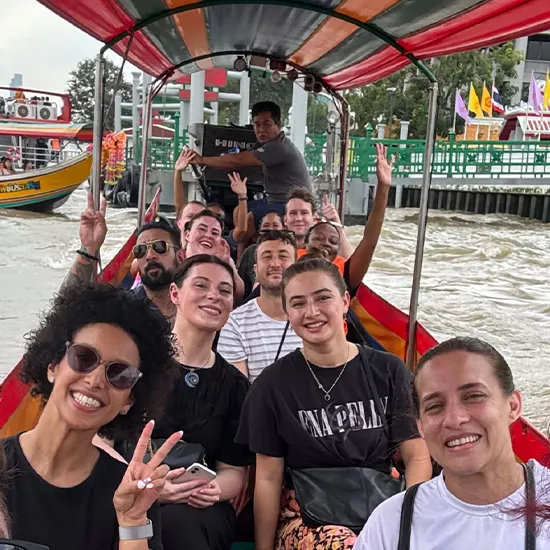 Group of people smiling on a long tail canal boat in Bangkok.