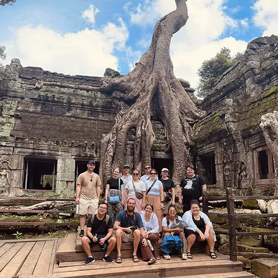 Group of people posing together in front of Ta Prohm temple in Angkor, Cambodia.