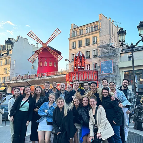 Topdeck travelers pose for a group photo in front of the Moulin Rouge cabaret house in Paris.