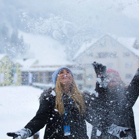 Topdeck travelers throwing snow into the air at the Swiss Alps.